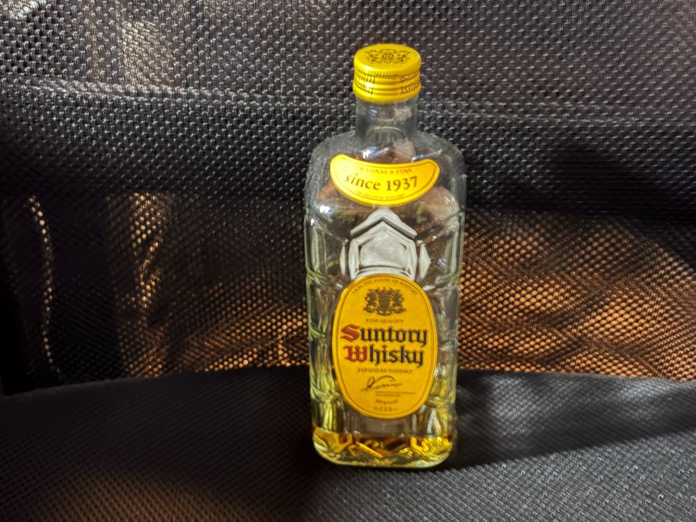 キャップを閉めたサントリー角瓶の正面と、ボトル下部に残った液体